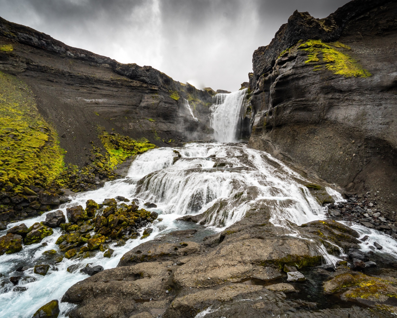 Быстрый горный водопад под серым небом
