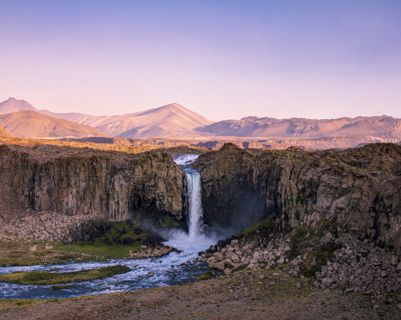 Водопад стекает по каменному склону горы на рассвете 