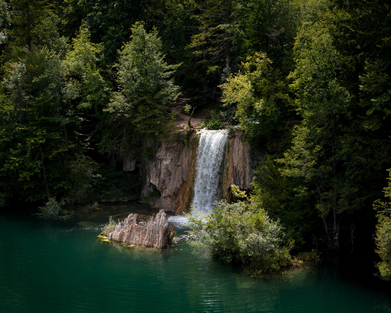 Водопад стекает со скалы в холодное озеро 