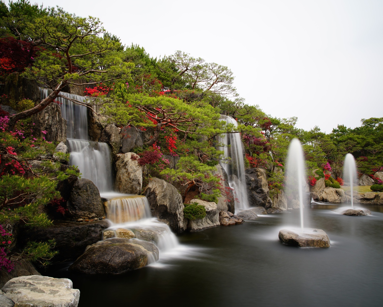 Водопады в красивом саду с зелеными деревьями