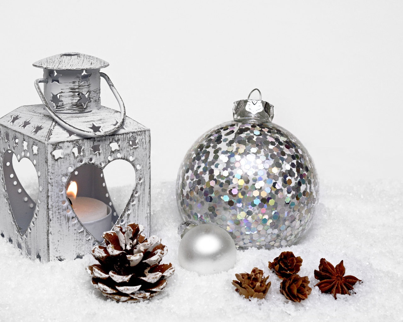 Фонарик и елочный шар с шишками на снегу