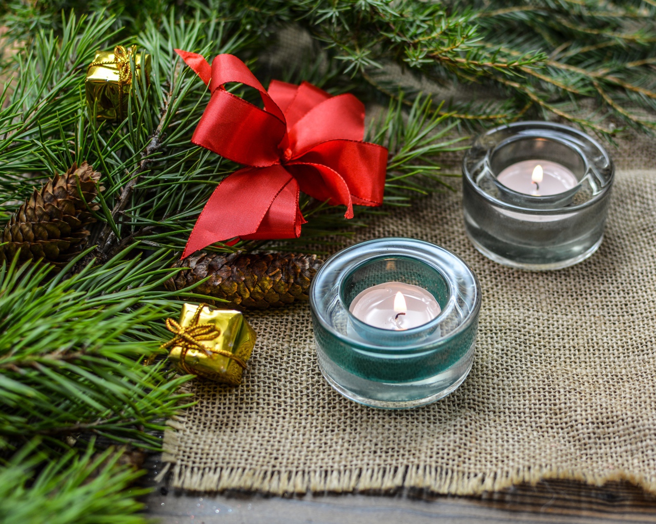Две зажженные свечи, еловая ветка и красный бант на рождество 