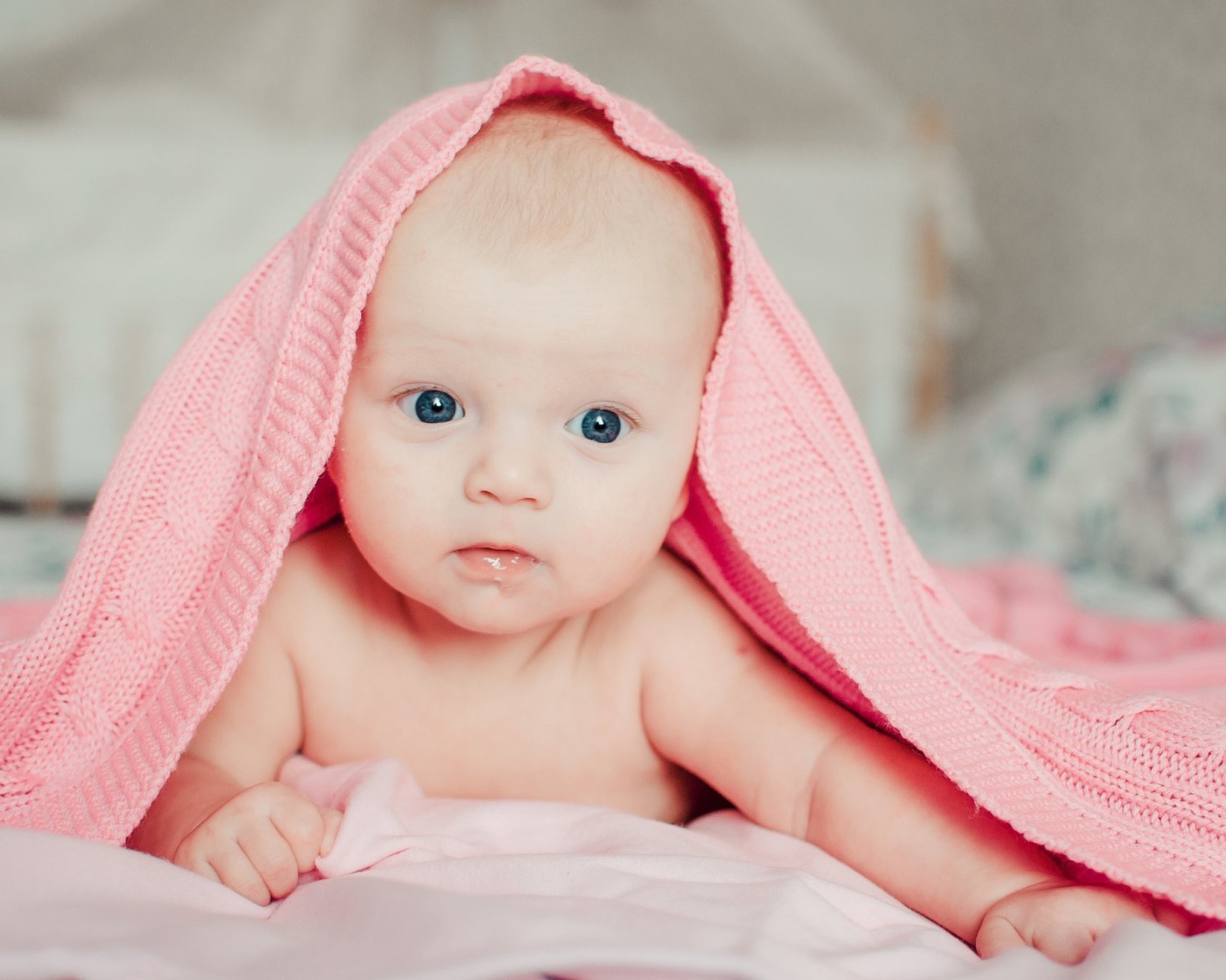 Грудной ребенок лежит под розовым пледом