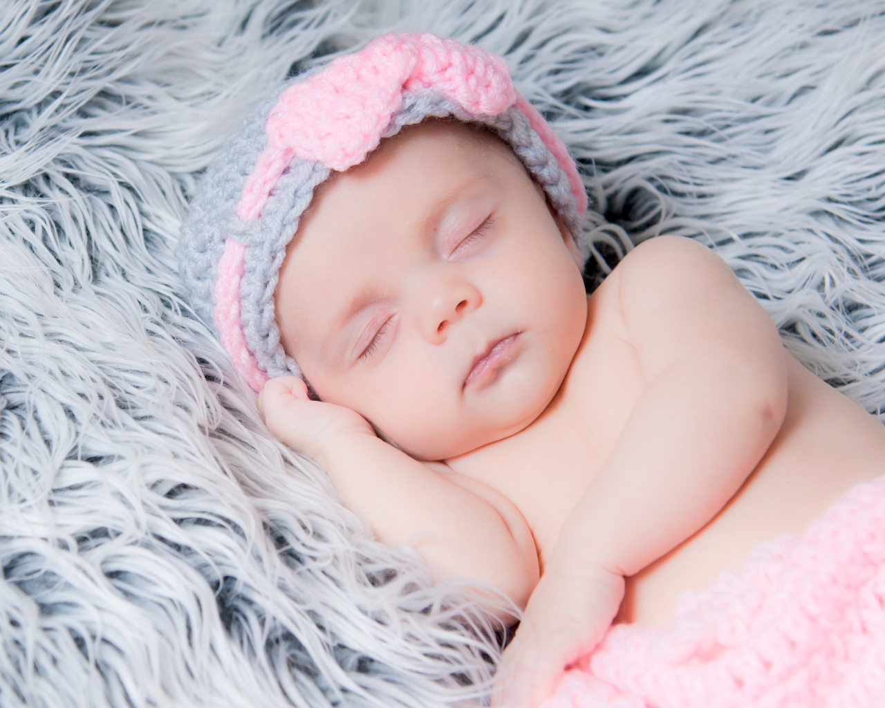 Грудной ребенок спит на меховом одеяле 