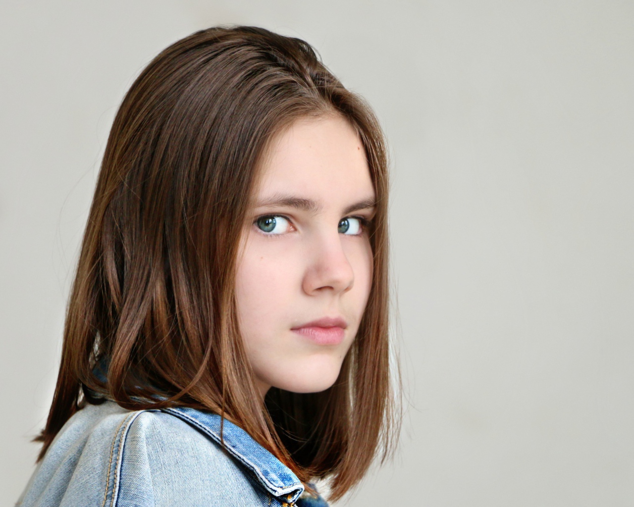 Красивая зеленоглазая девочка на сером фоне