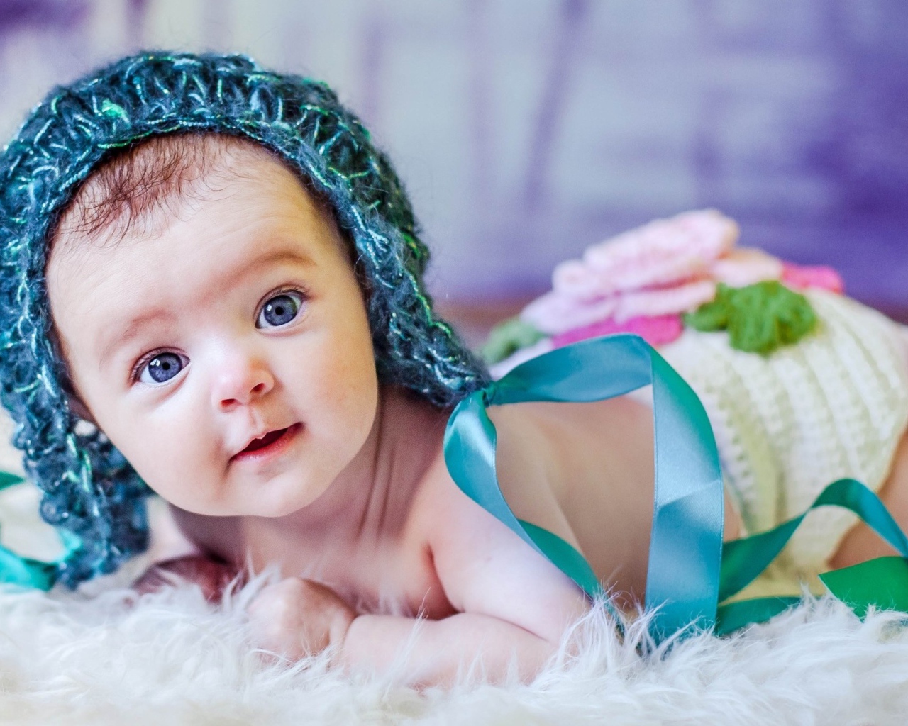 Голубоглазая маленькая девочка в вязаной шапке с ленточками