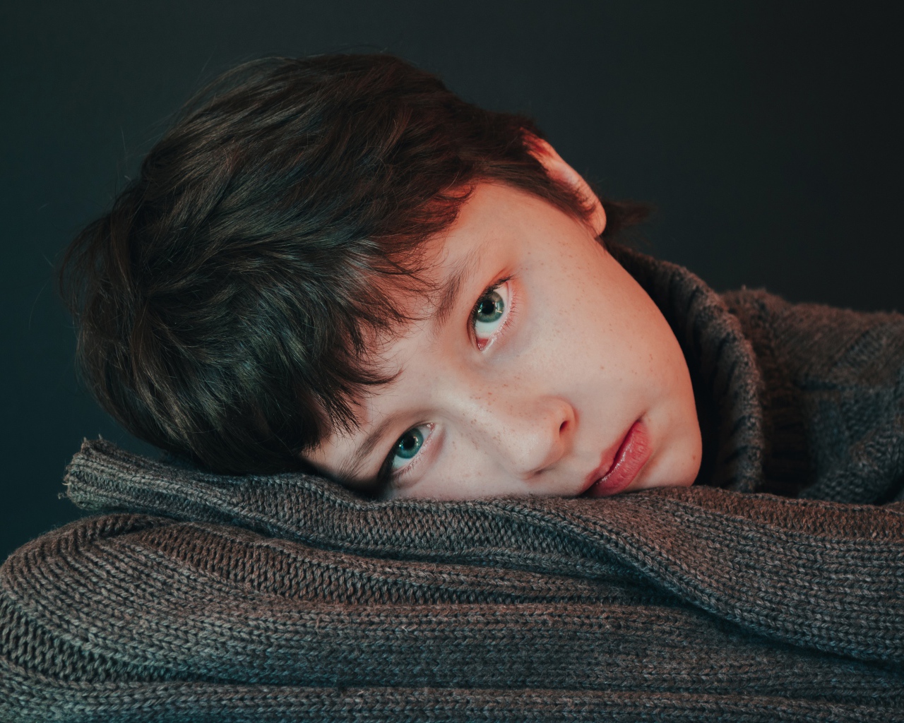 Мальчик в теплом свитере на сером фоне 