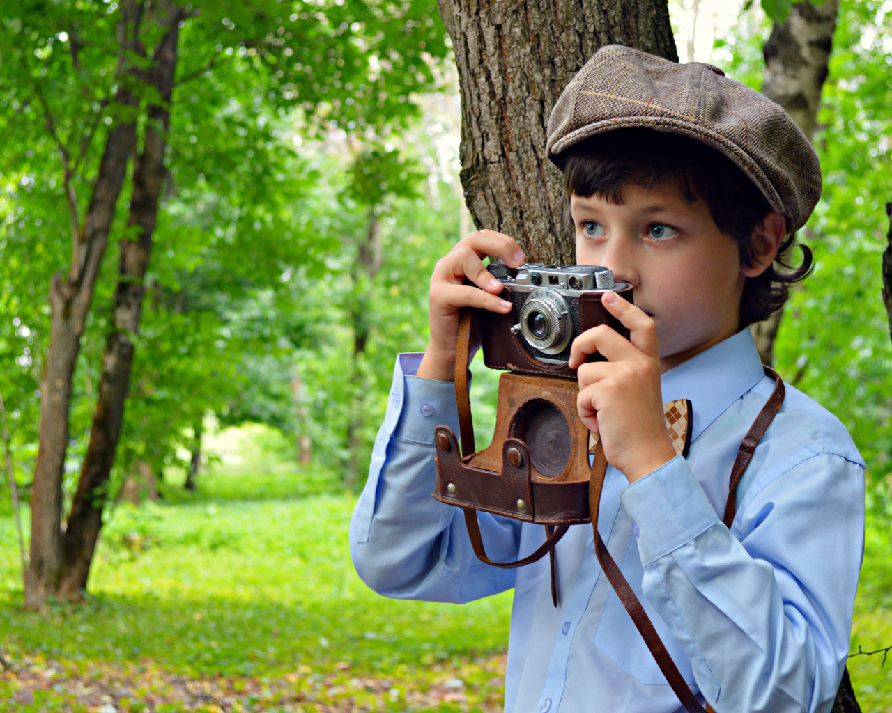 Мальчик с фотоаппаратом в руках в парке