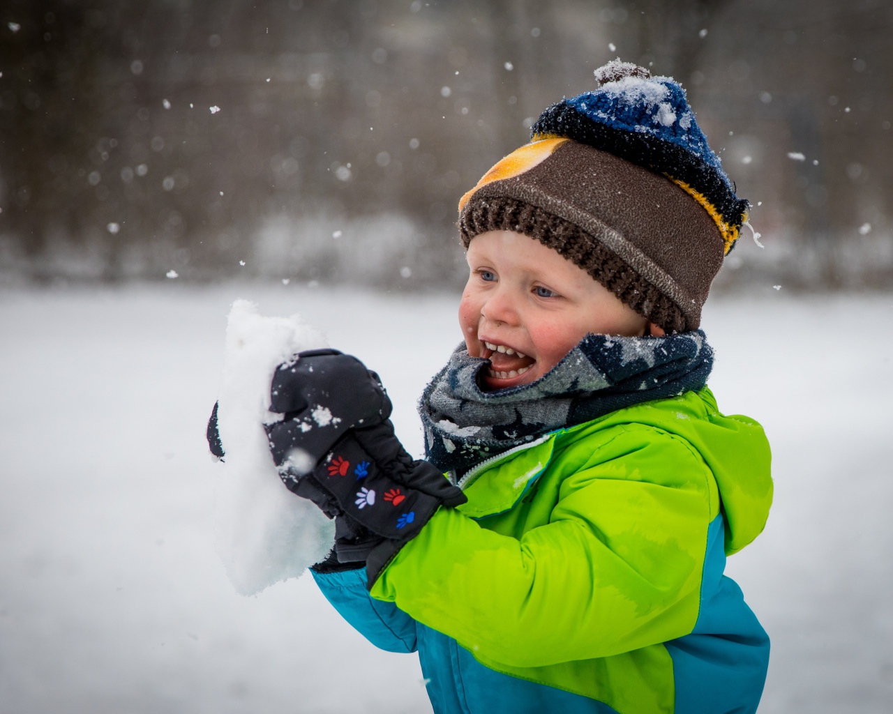 Веселый маленький мальчик со снегом в руках 
