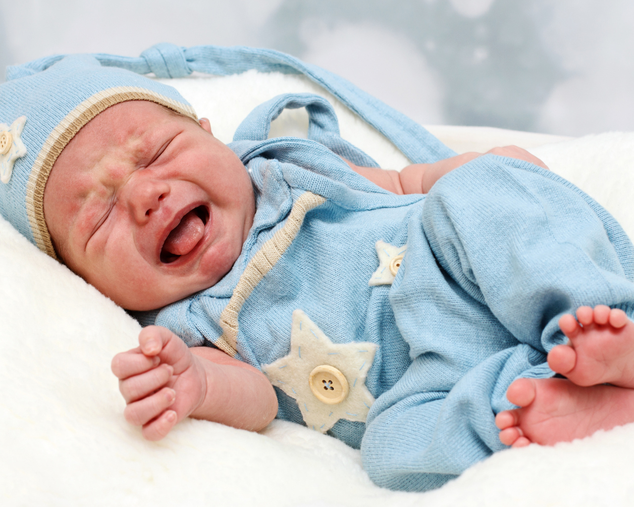 Плачущий грудной ребенок в голубом костюме