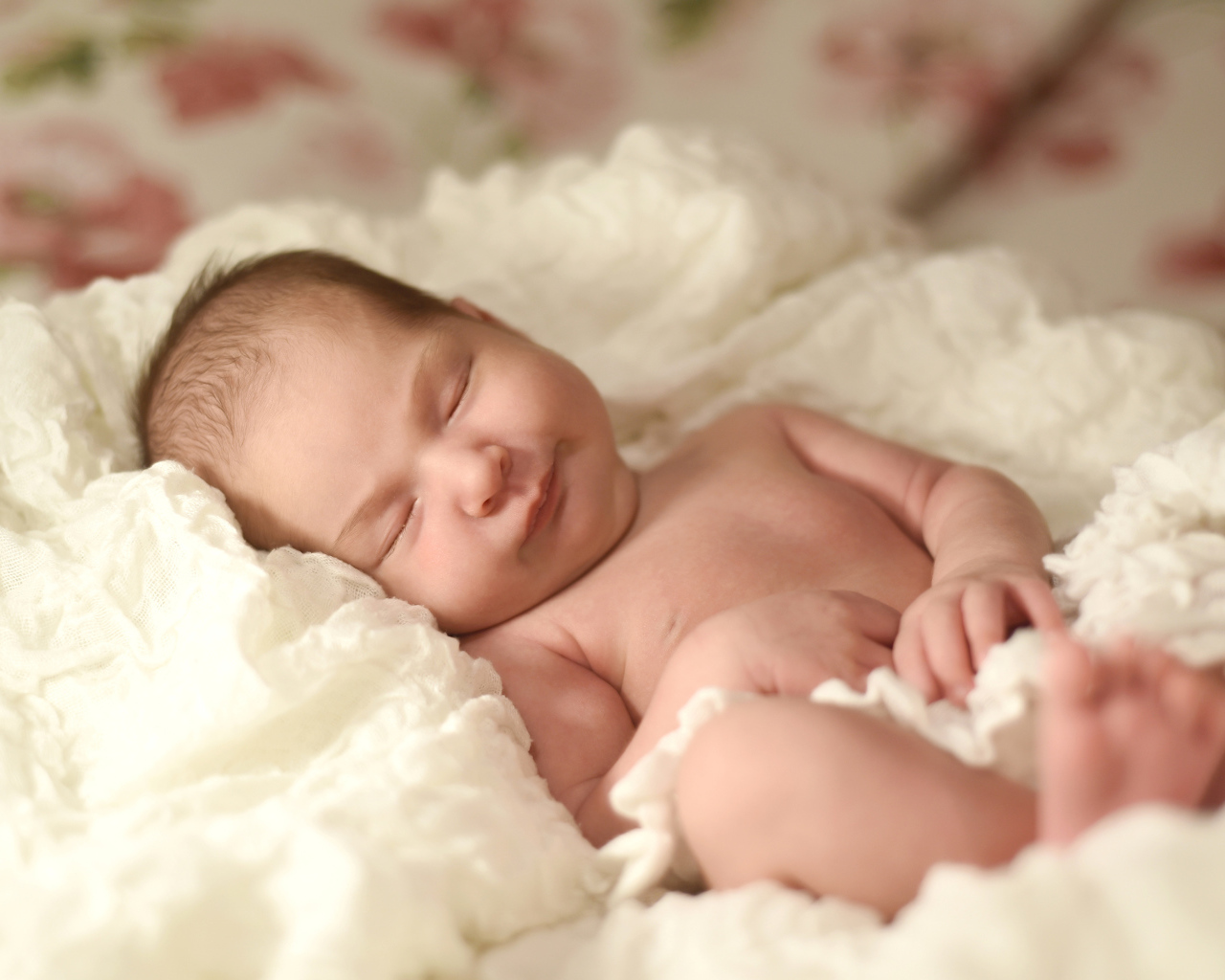 Милый грудной ребенок спит на белом покрывале 