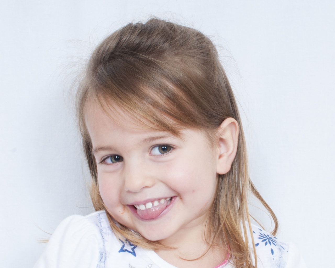 Милая улыбающаяся девочка с высунутым языком