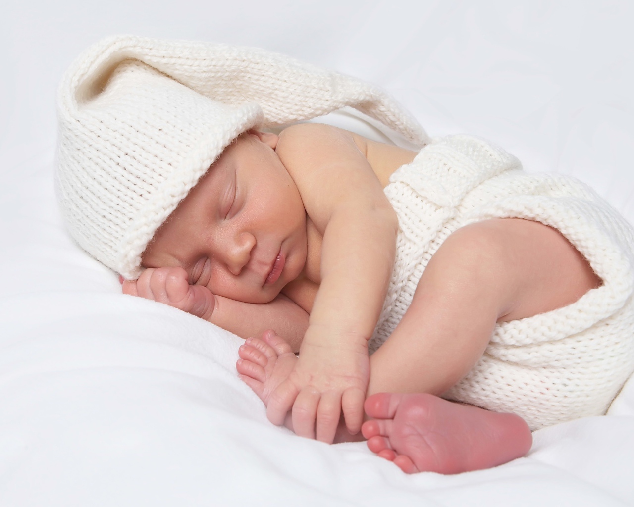 Нежный новорожденный ребенок в белом костюме