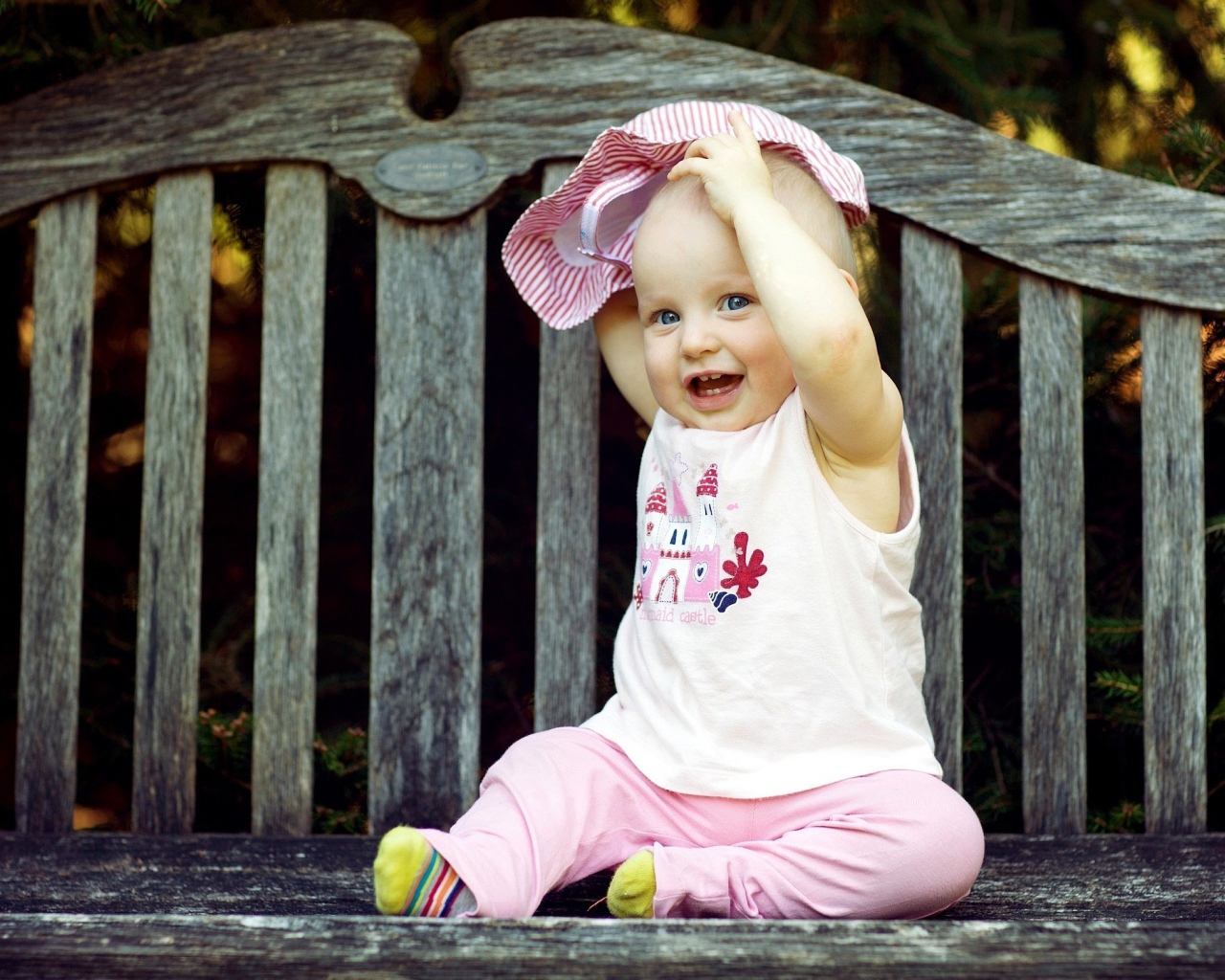 Смешной маленький ребенок сидит на лавке