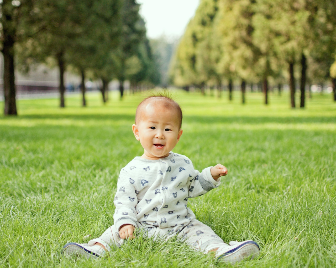 Маленький ребенок азиат сидит на зеленой траве 