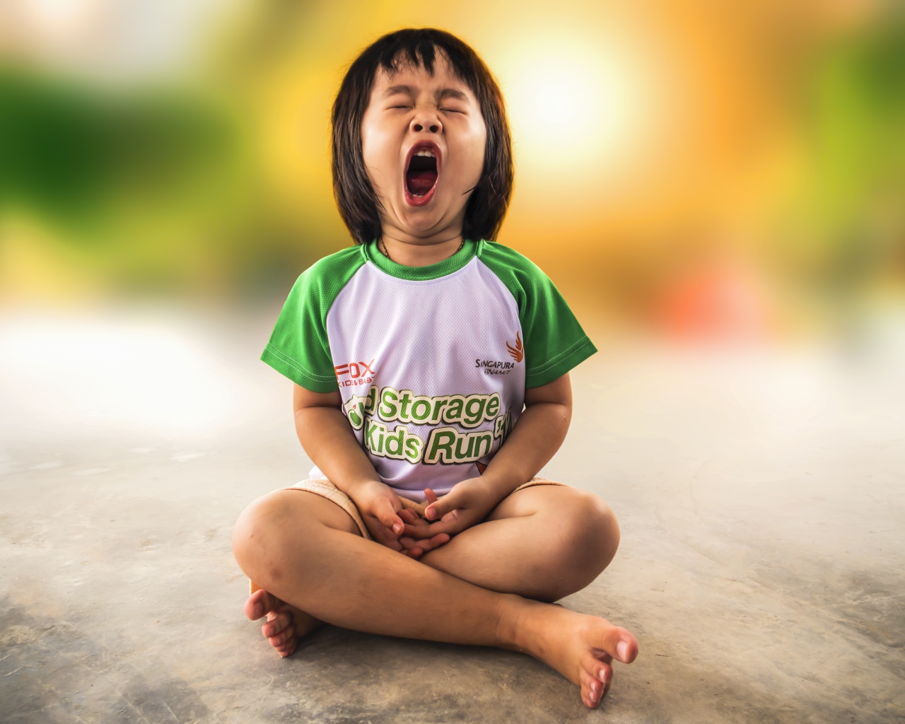 Маленькая девочка азиатка зевает на полу