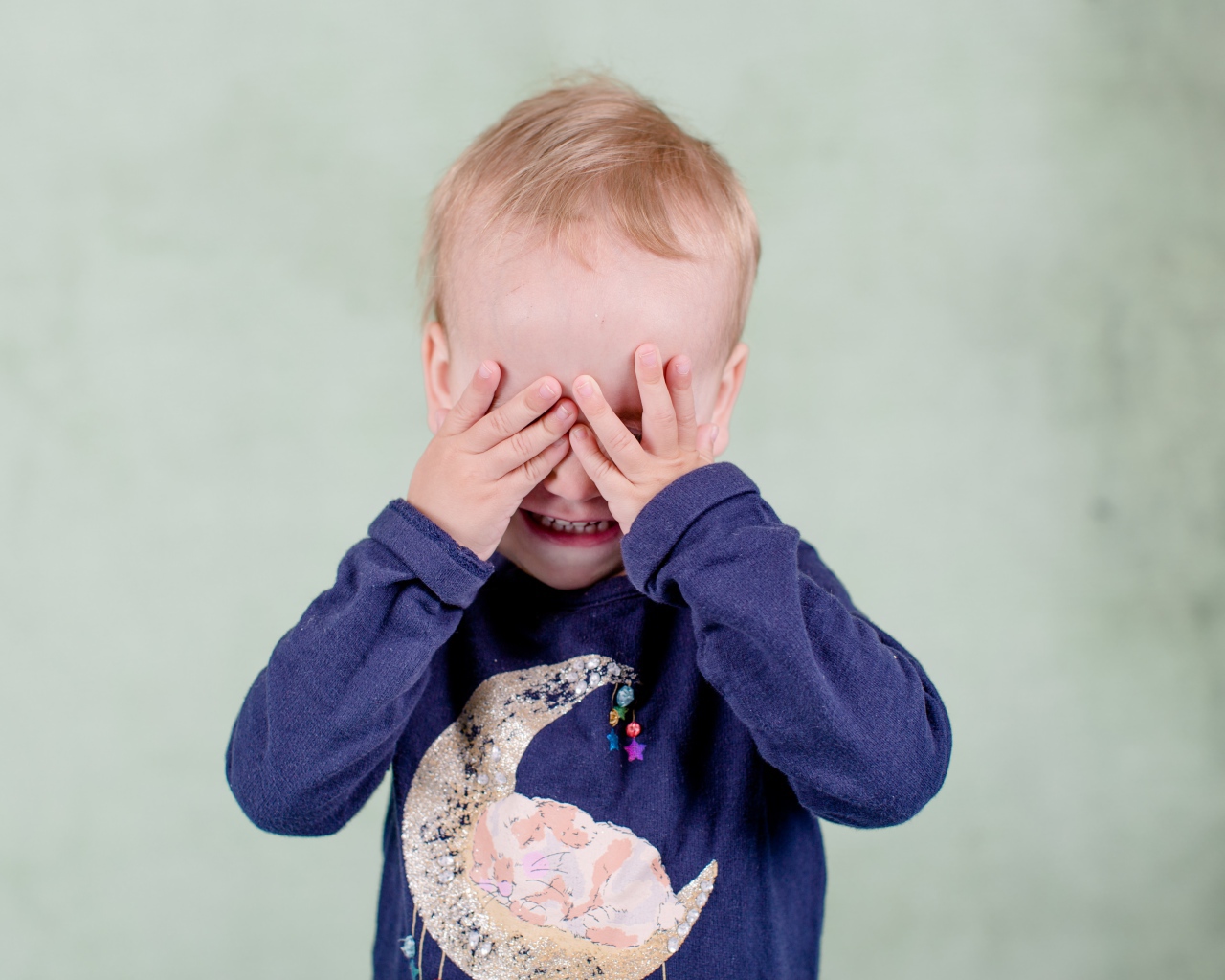 Маленький мальчик закрыл руками лицо 