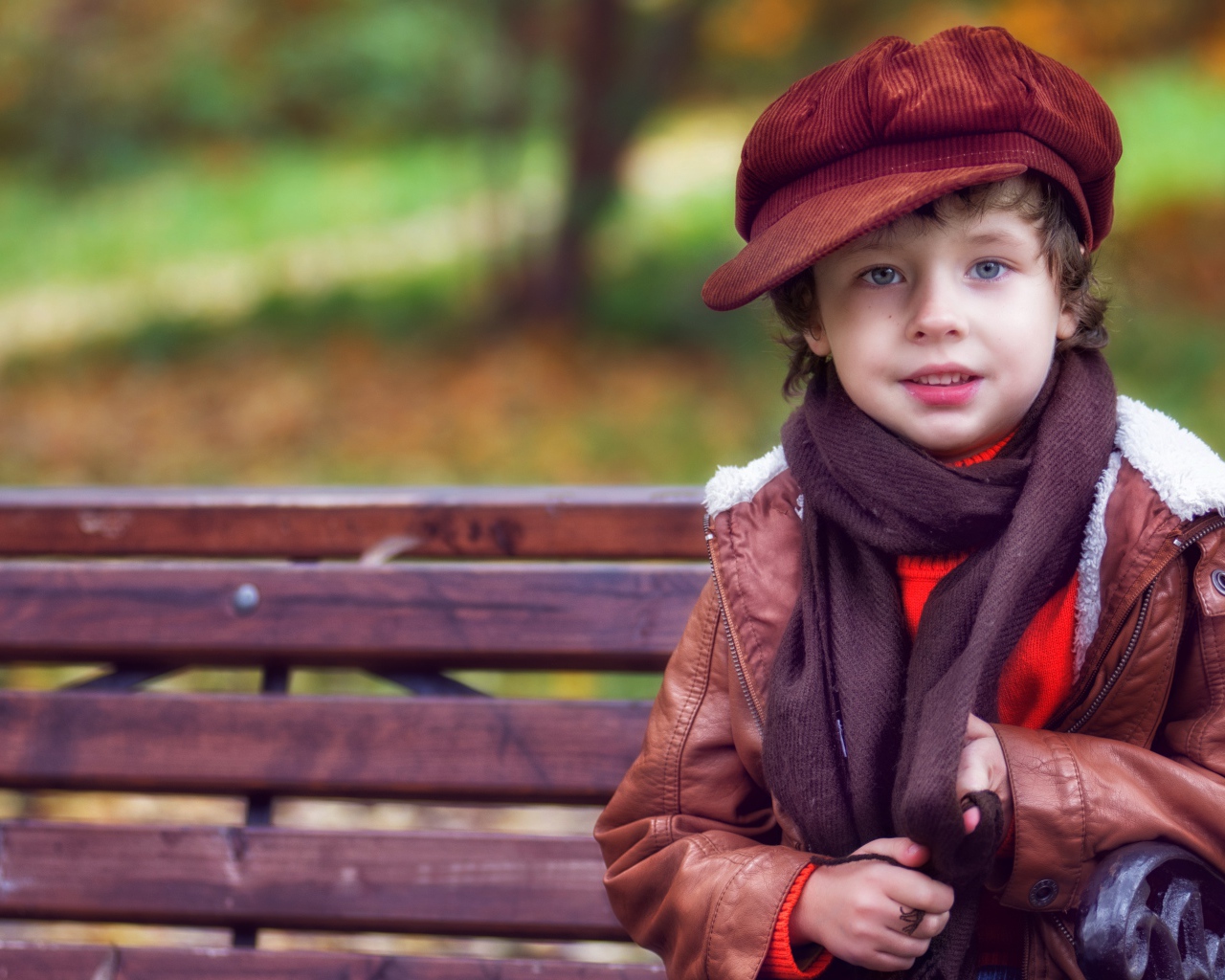Маленький мальчик в кепке сидит на лавке