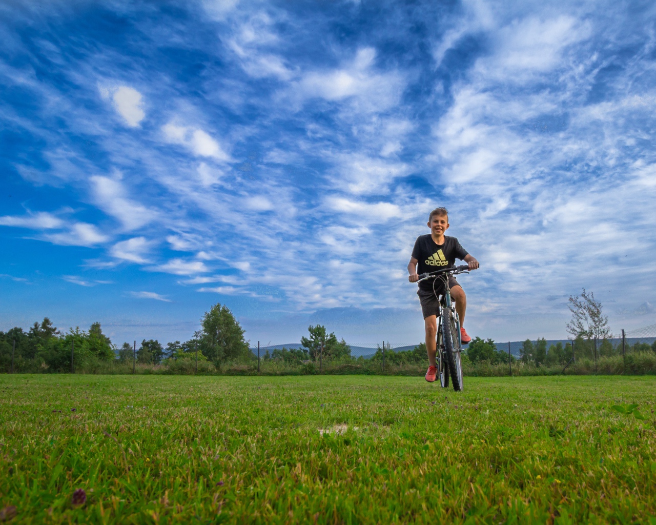 Маленький мальчик катается на велосипеде по полю 
