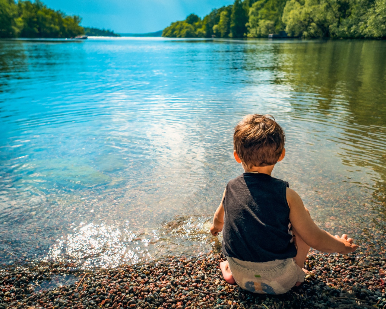 Маленький мальчик кидает камни в воду
