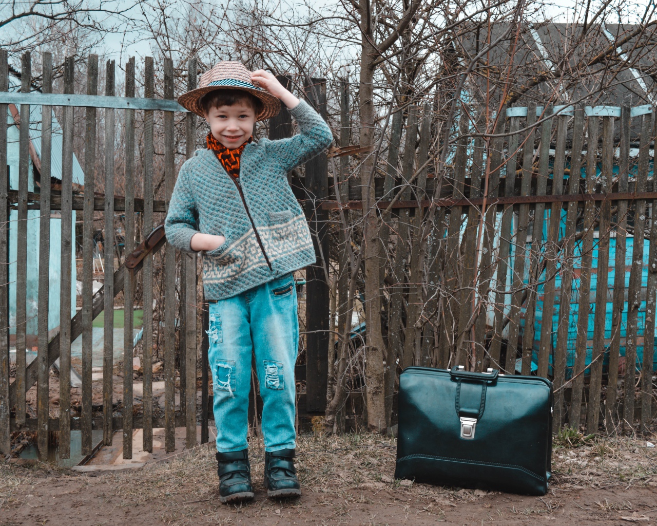 Маленький мальчик с чемоданом у забора