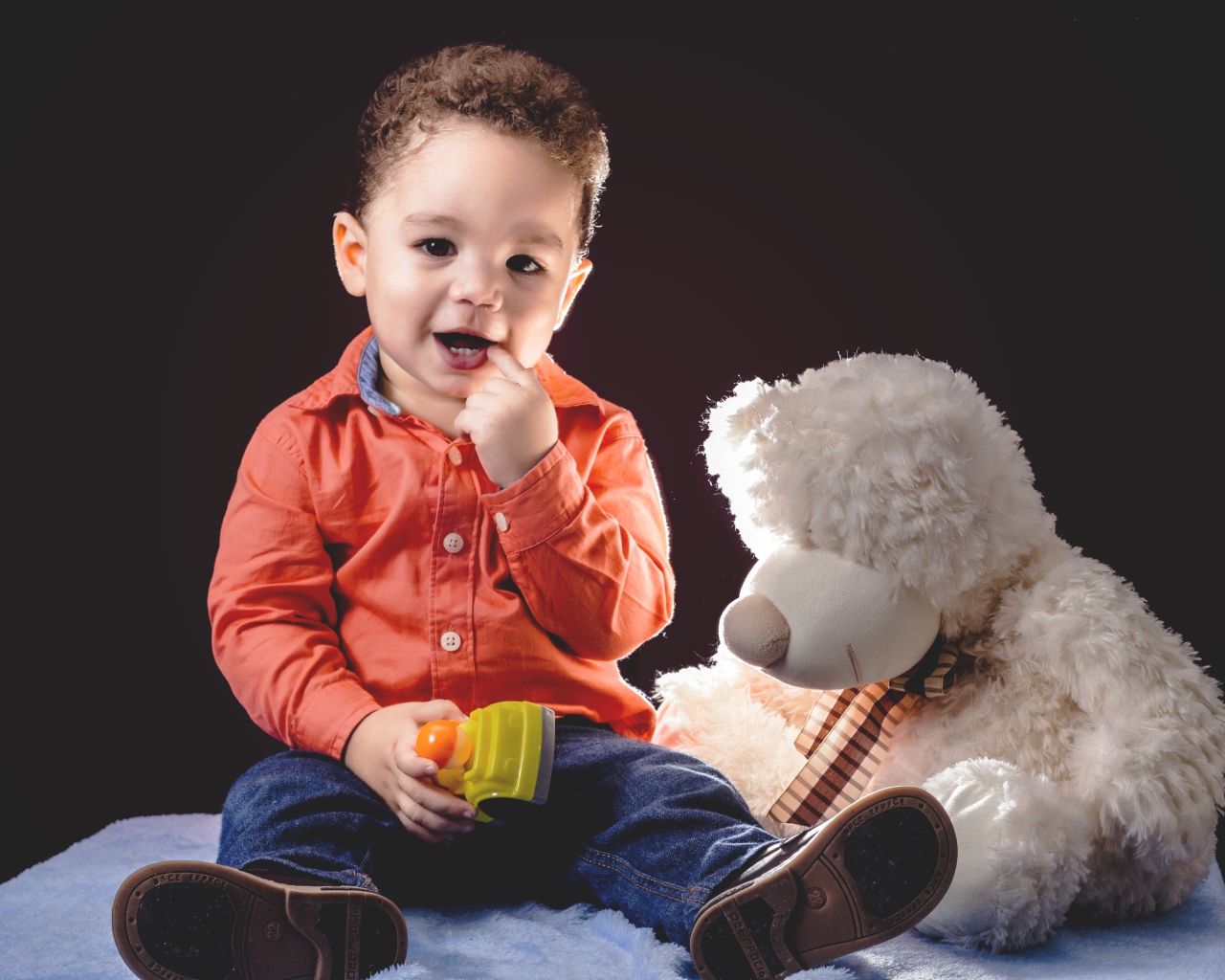 Маленький мальчик с игрушечным медведем на черном фоне