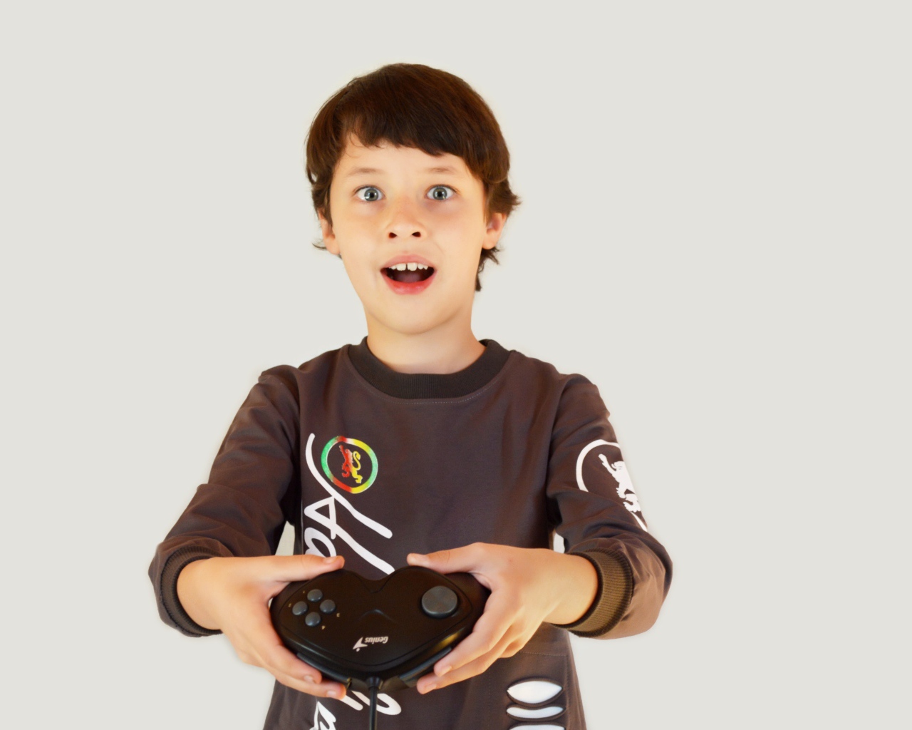 Маленький мальчик с приставкой на сером фоне 