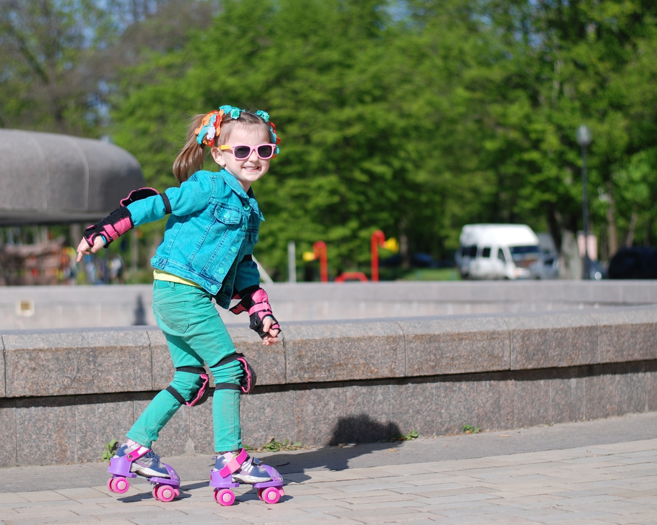 Маленькая веселая девочка катается на роликах