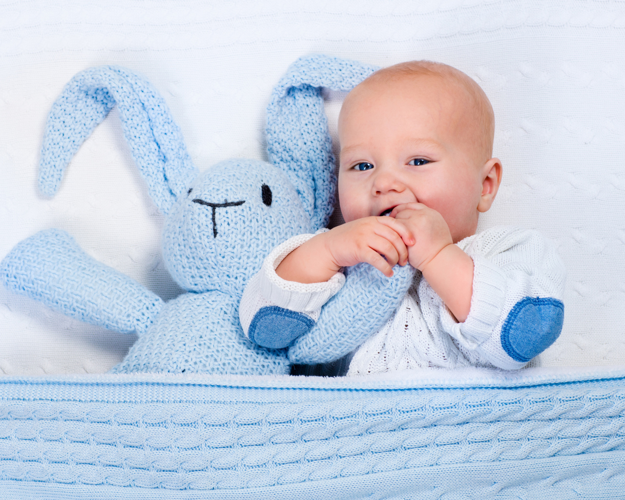 Маленький ребенок кусает игрушечного зайца 