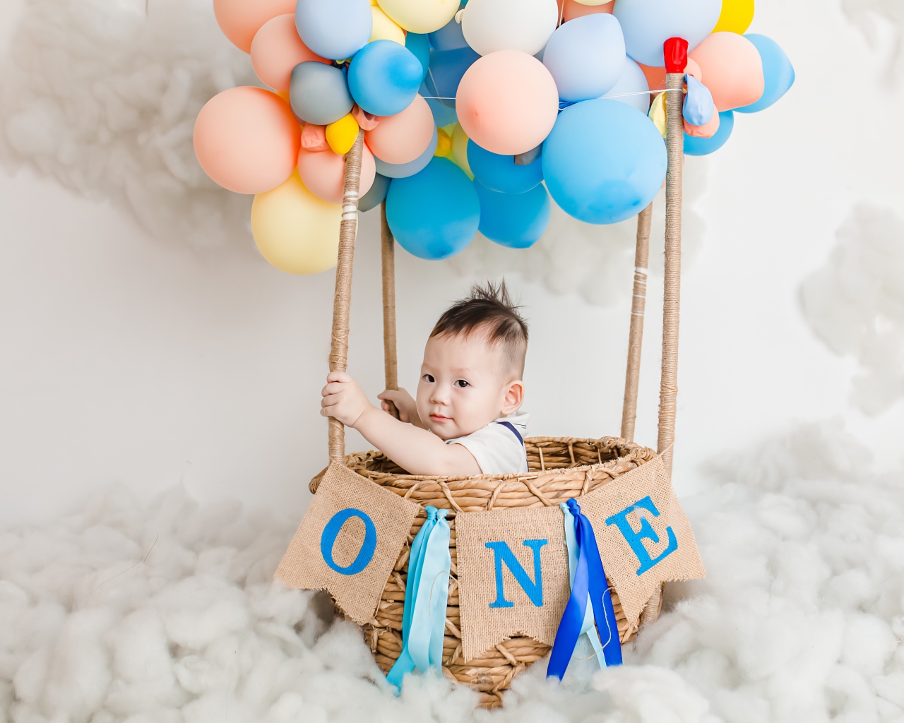 Маленький ребенок в корзине с шариками 