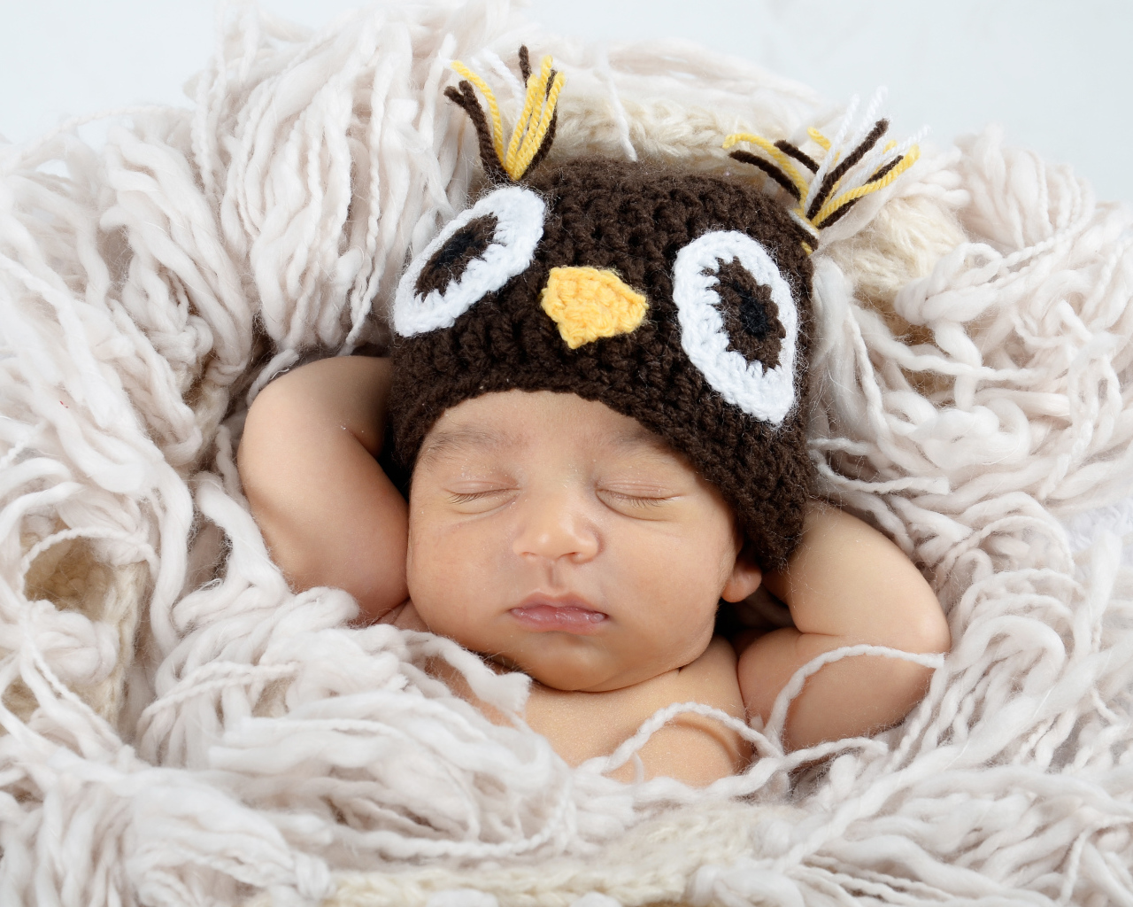 Маленький ребенок  в вязаной шапке спит на кровати 