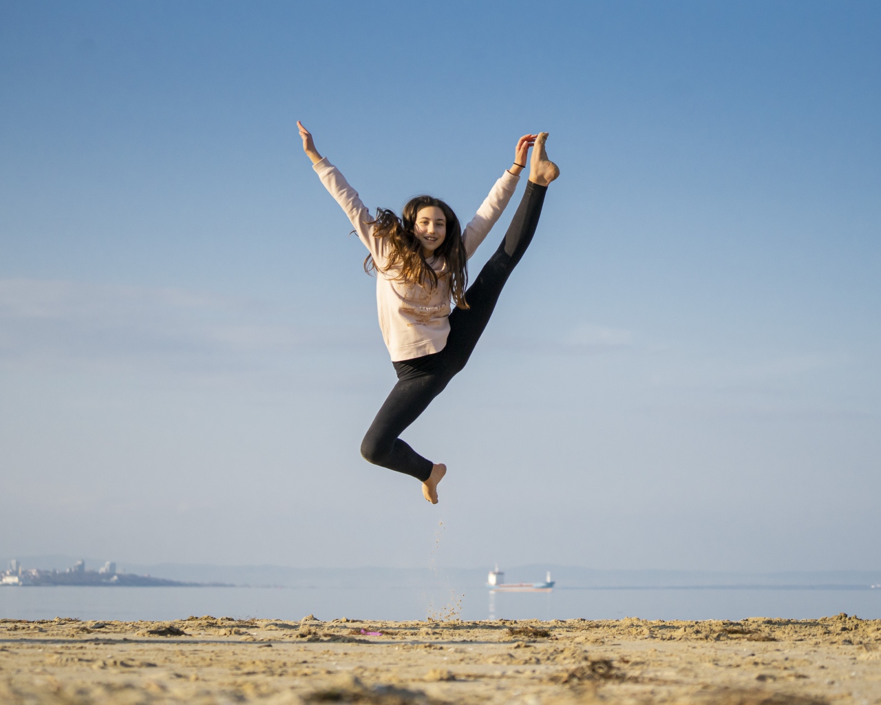 Маленькая девочка гимнастка на песке