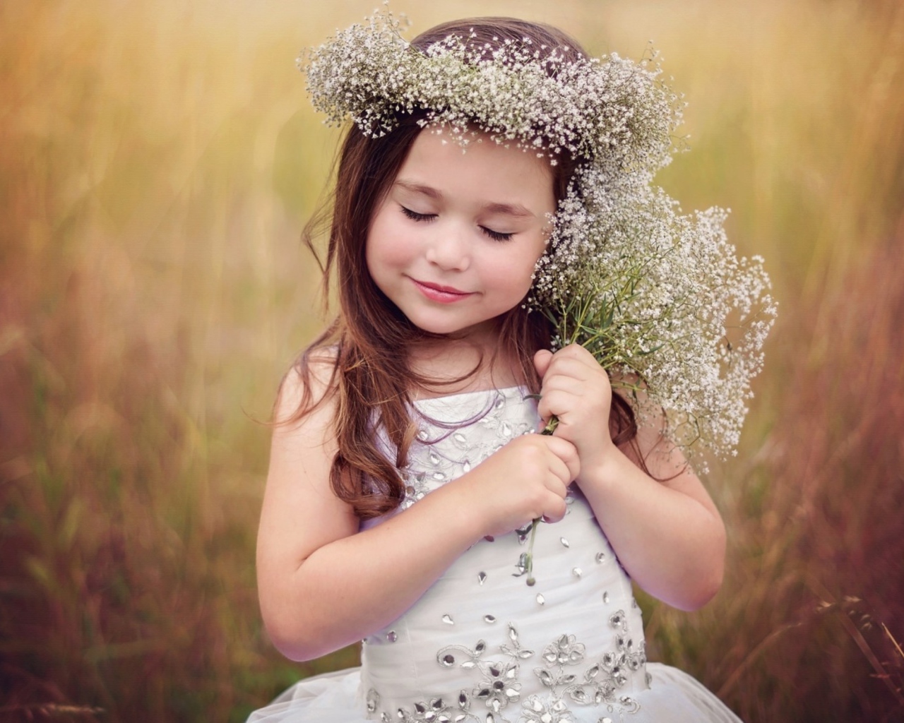 Маленькая девочка в венке с букетом полевых цветов