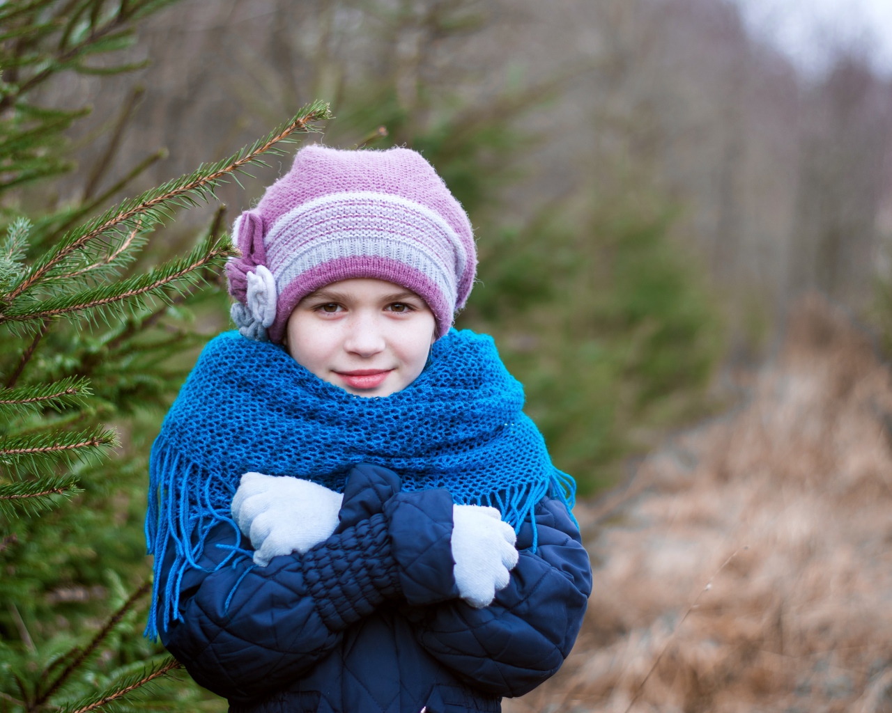 Маленькая девочка в теплой одежде у ели