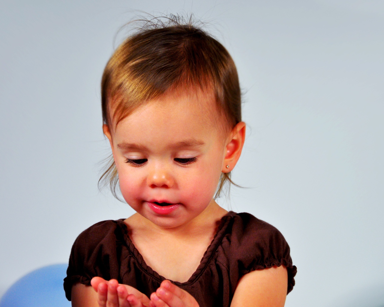 Маленькая девочка смотрит на руки на сером 