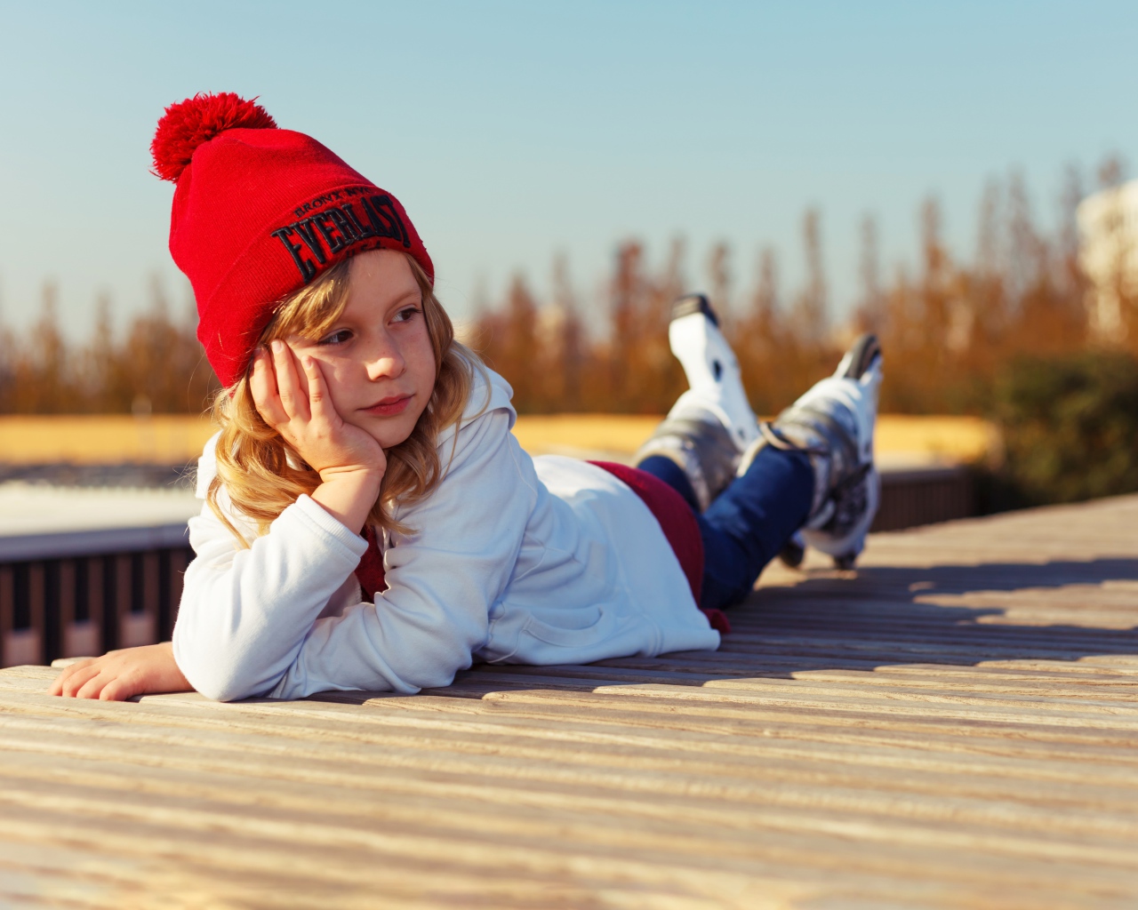 Маленькая девочка на роликах лежит на мосту