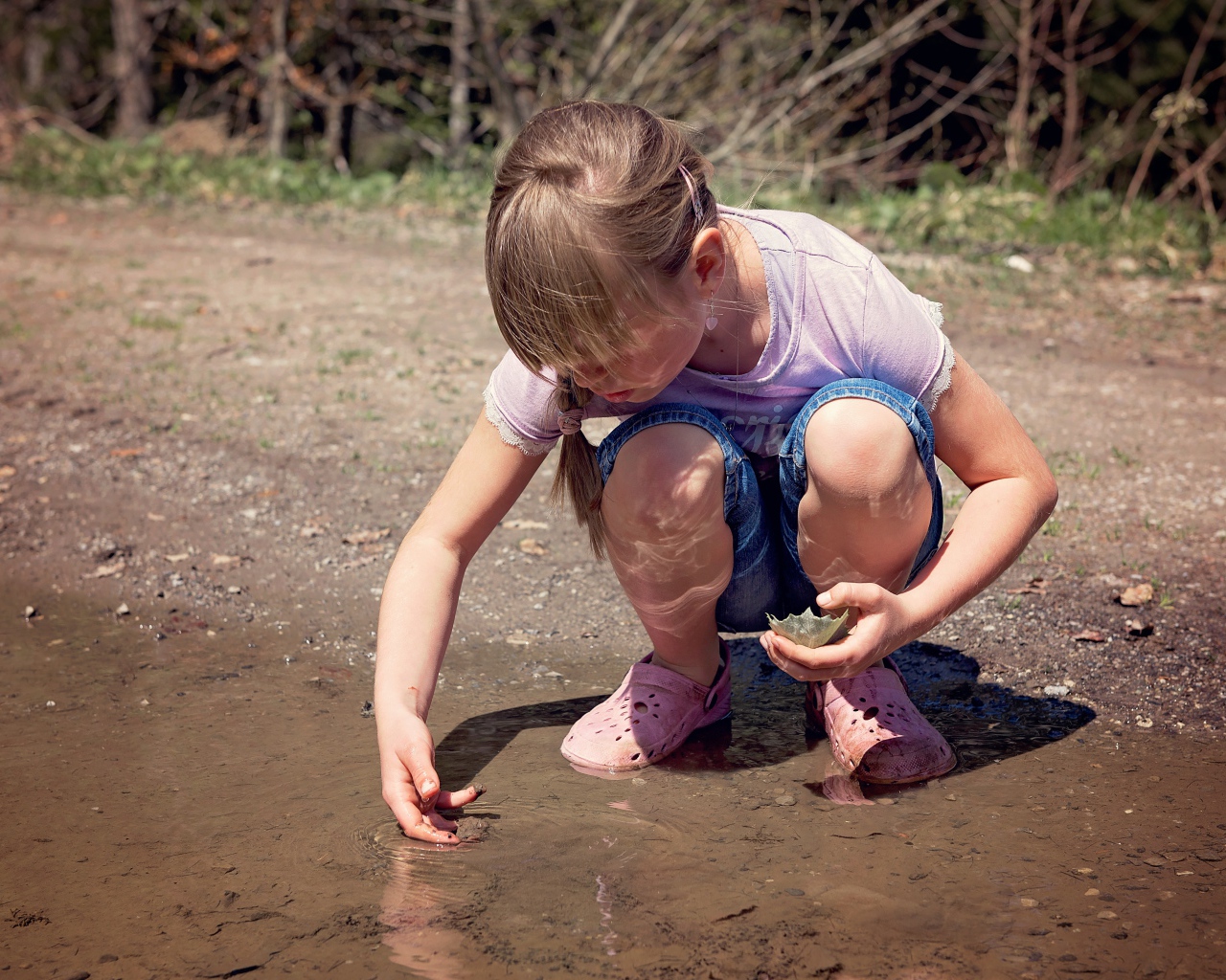 Маленькая девочка играет в луже 
