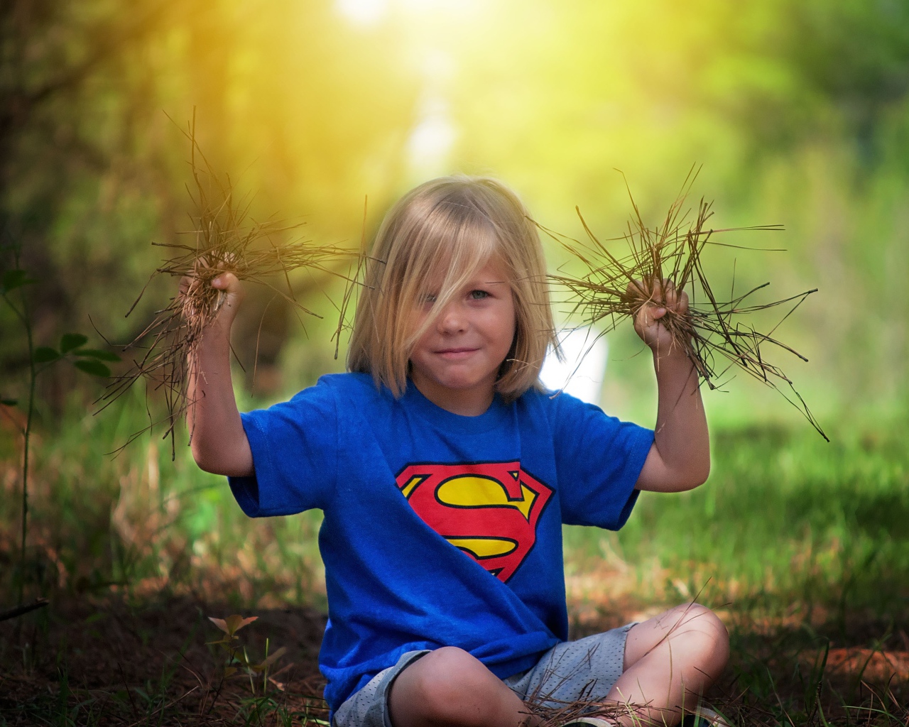 Маленькая девочка сидит на земле с травой