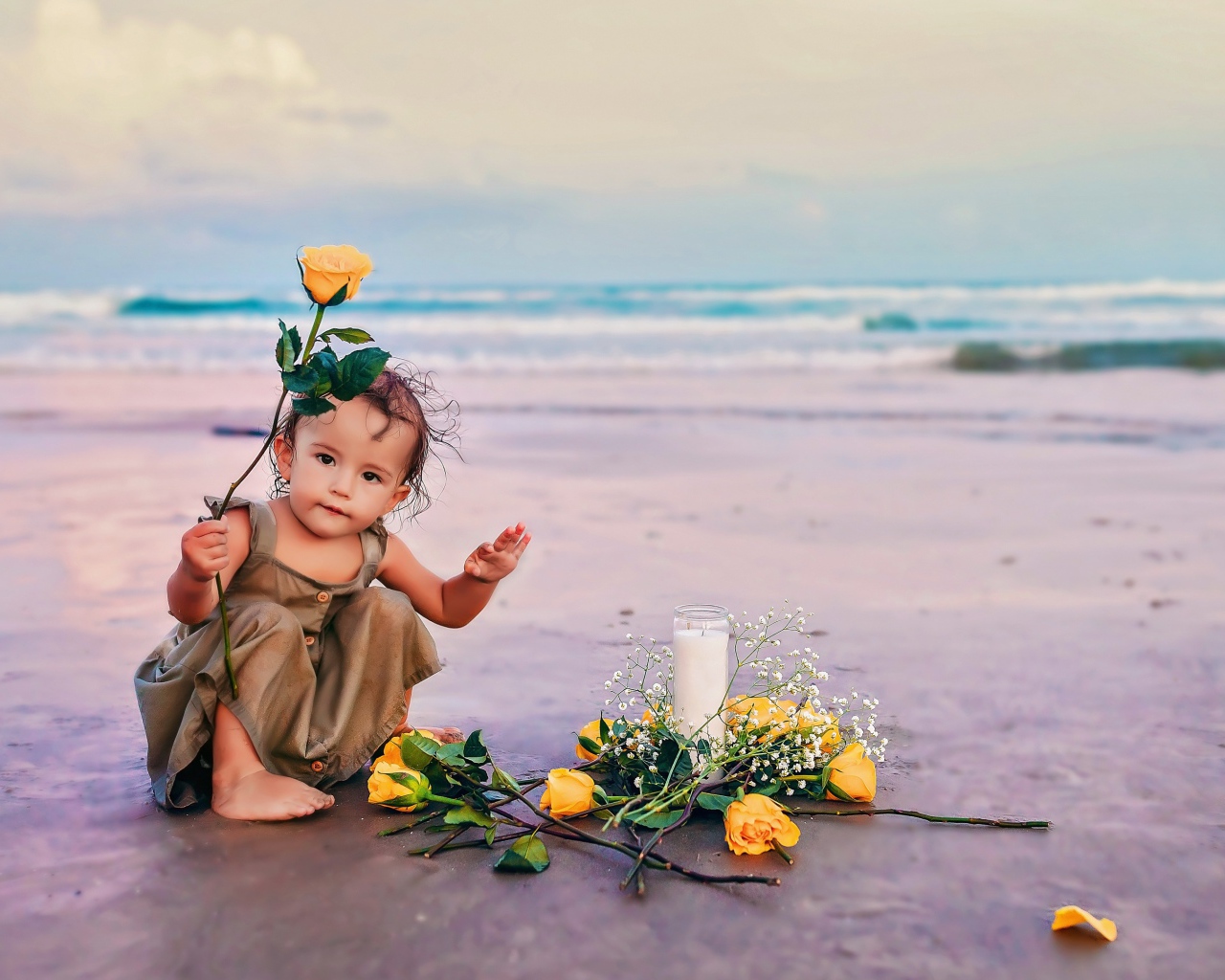 Маленькая девочка сидит на песке с розами 