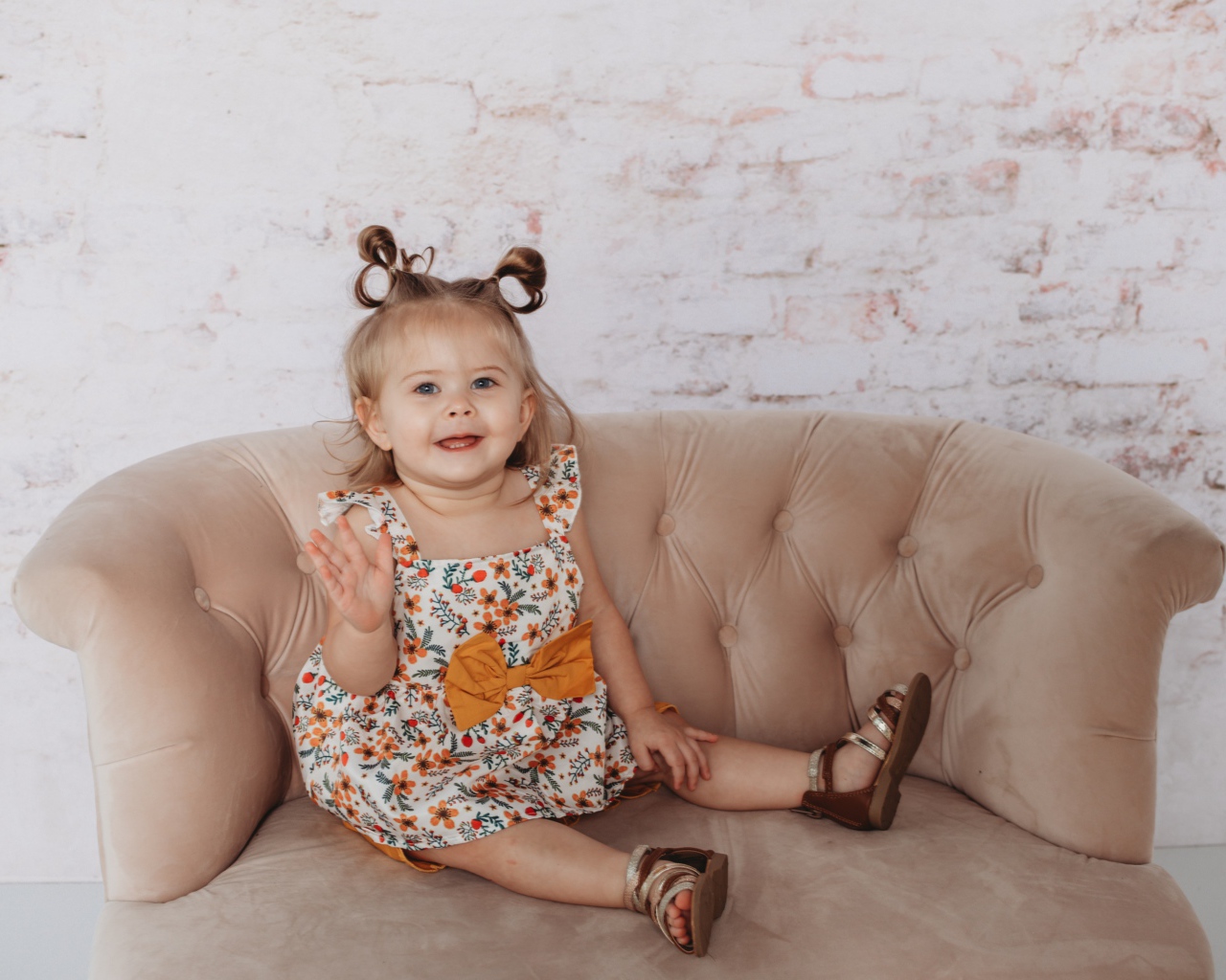 Маленькая девочка сидит на диване у стены