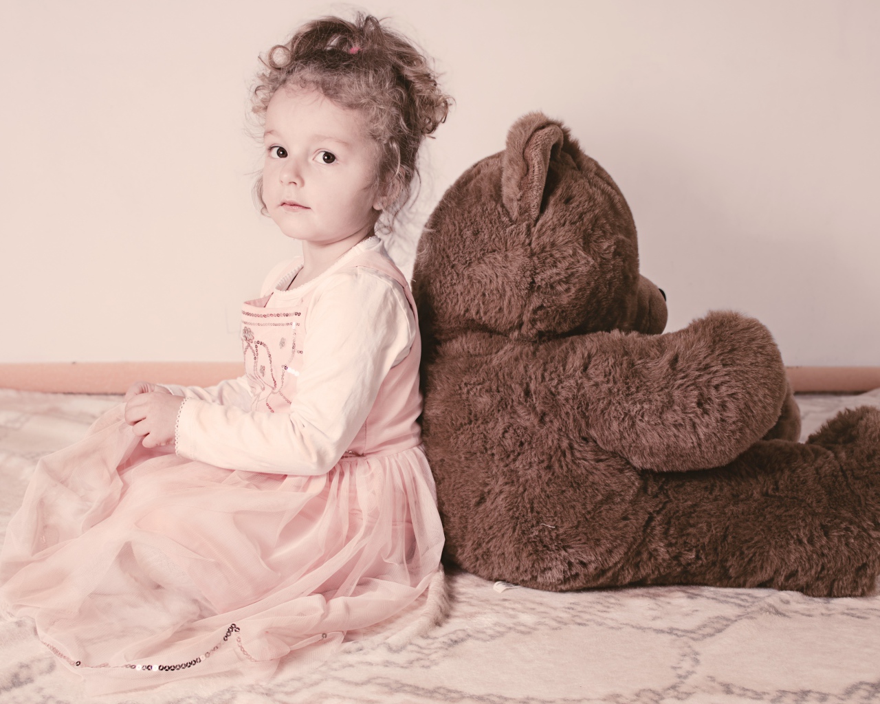 Маленькая девочка сидит с большим медведем