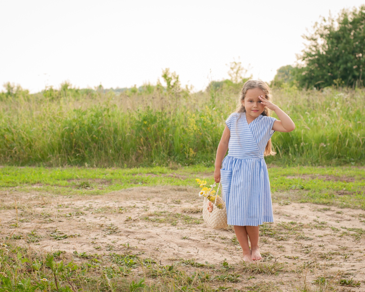 Маленькая девочка с сумкой на поле с травой 