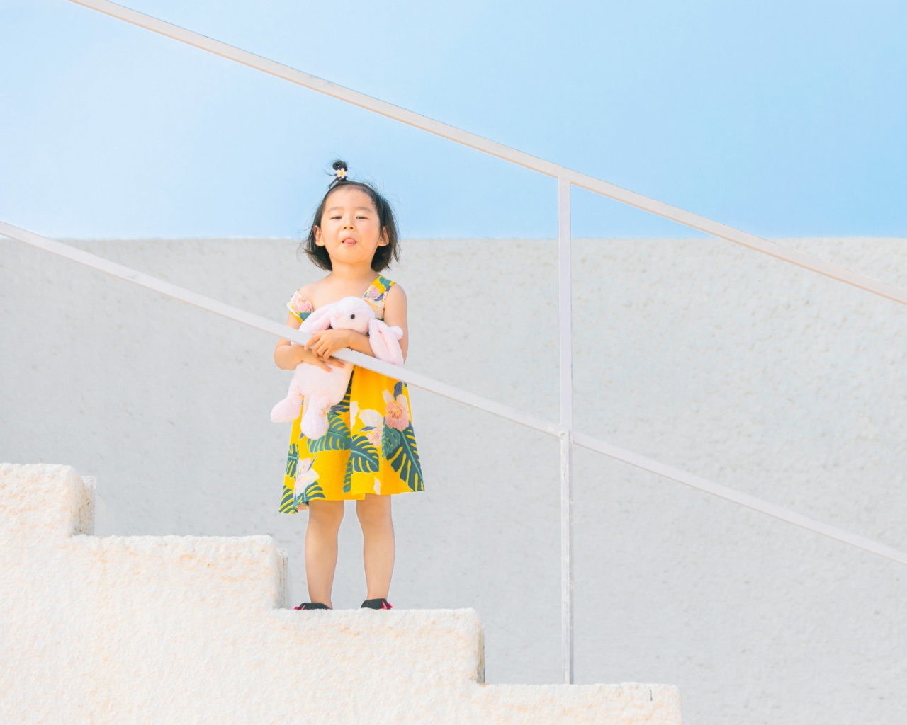 Маленькая девочка с игрушкой на ступеньках 