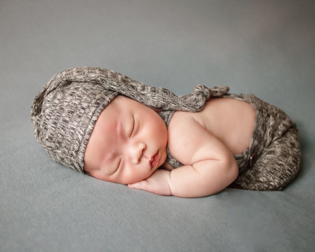 Маленький новорожденный ребенок на сером фоне