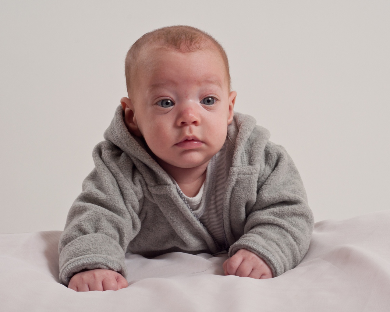 Маленький новорожденный мальчик в сером костюме