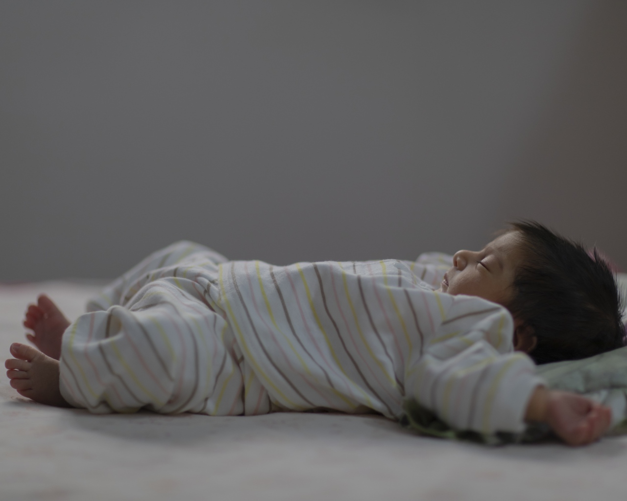 Маленький спящий грудной ребенок на кровати 