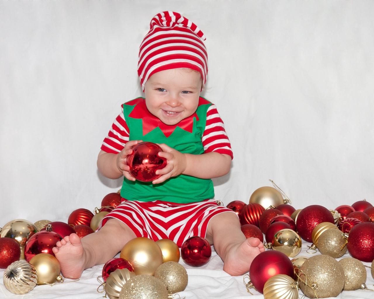 Маленький улыбающийся мальчик с елочными украшениями