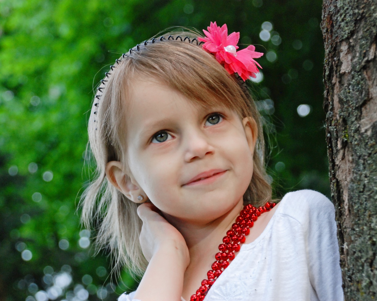 Маленькая улыбающаяся девочка у дерева 