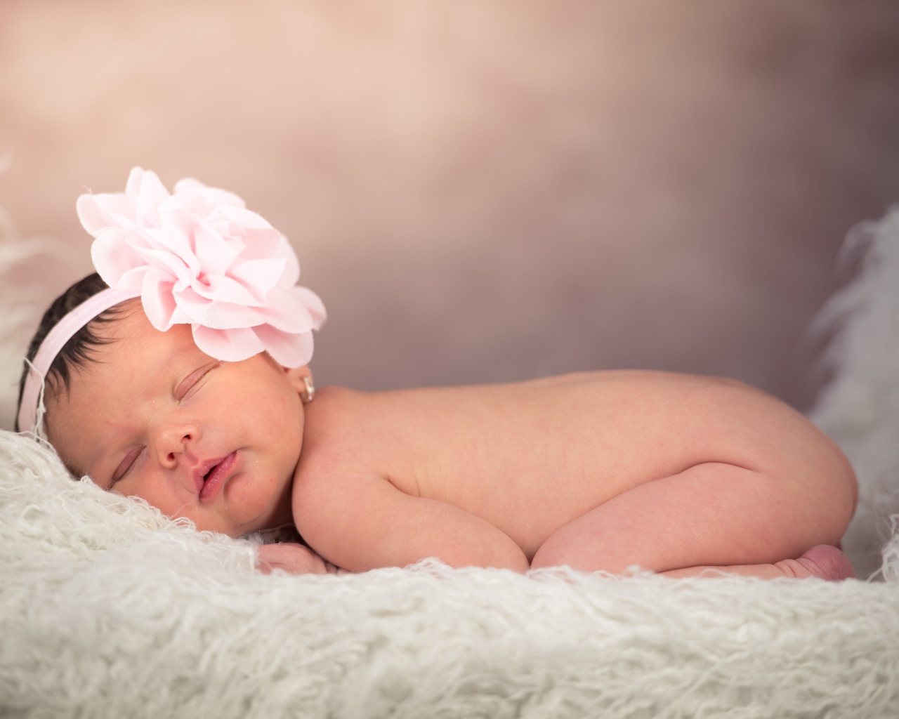 Новорожденная девочка с большим цветком на голове 