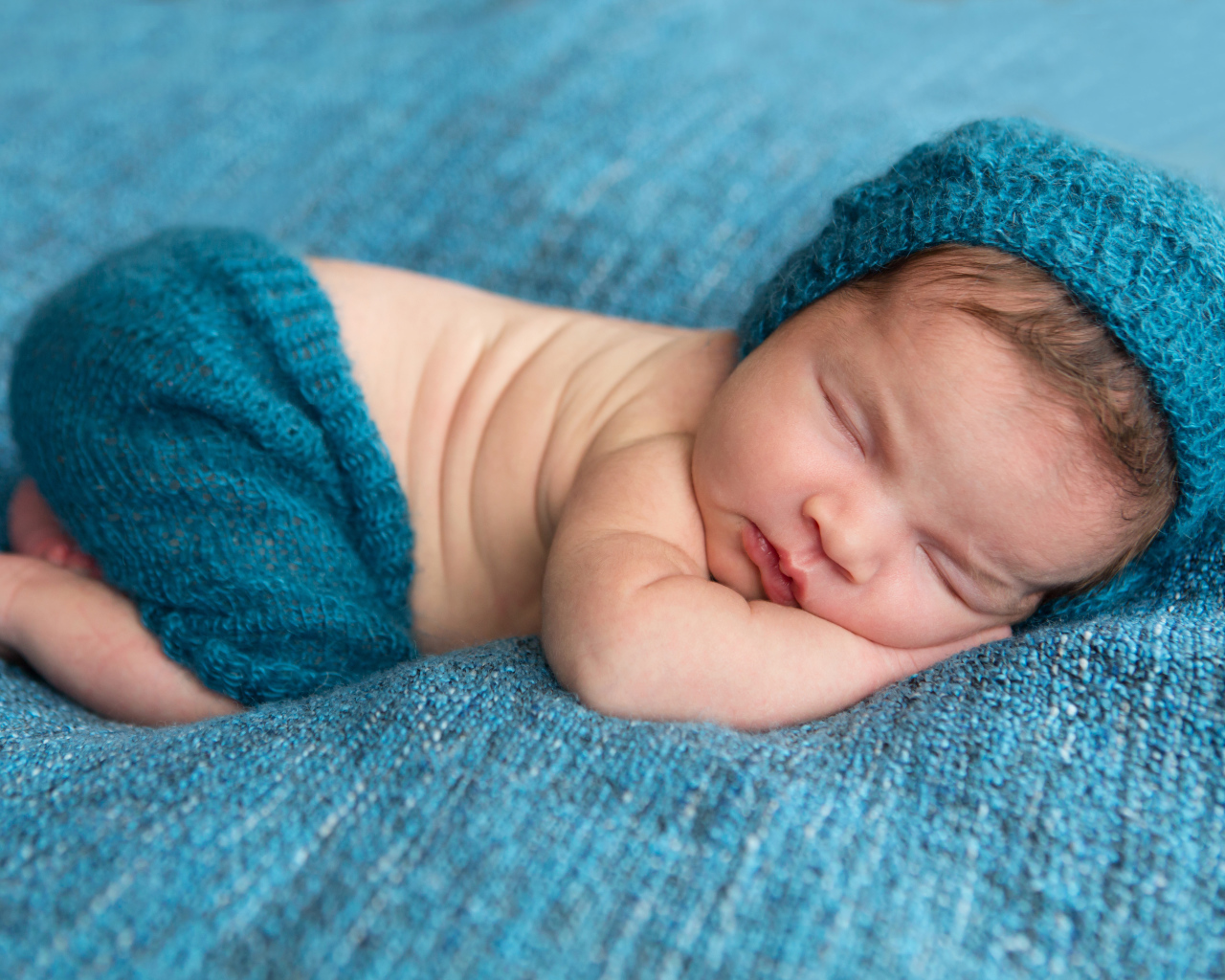 Спящий грудной ребенок лежит на голубом покрывале 